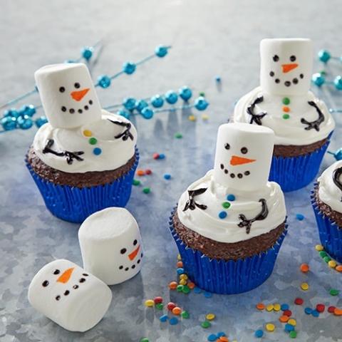 cupcakes with frosting and marshmallow decorations that looks like a melted snowman
